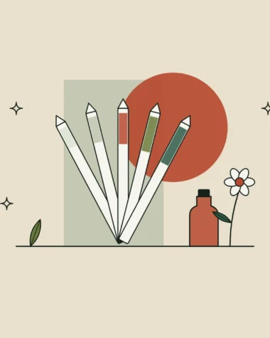 Abanico de tiras de papel para oler perfume junto a una flor y un pequeño frasco de esencia