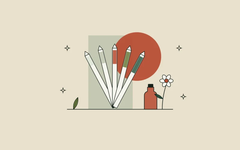 Abanico de tiras de papel para oler perfume junto a una flor y un pequeño frasco de esencia